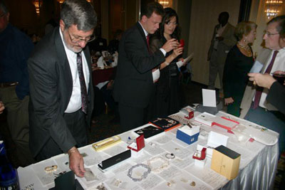 At silent auction table, Dennis Nelson, Michael Veasley with Mila Gonzalez prepare to bid while John Lees admires the goods!
